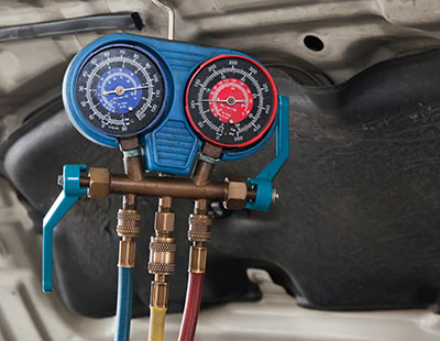 AC manifold gauges measuring refrigerant pressure during a mobile car AC repair in Jackson MS