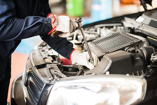 Mobile mechanic in Jackson MS repairing a car engine on-site with a ratchet wrench