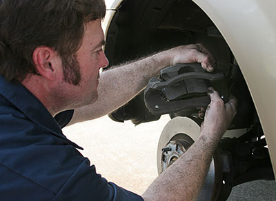 Mobile mechanic in Jackson MS servicing brake pads and rotors at a vehicle's wheel